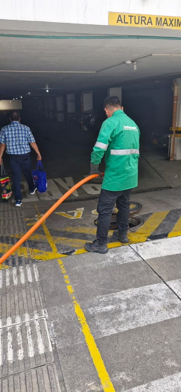 Operario de Fumisantander maniobrando la manguera en una trampa de grasa